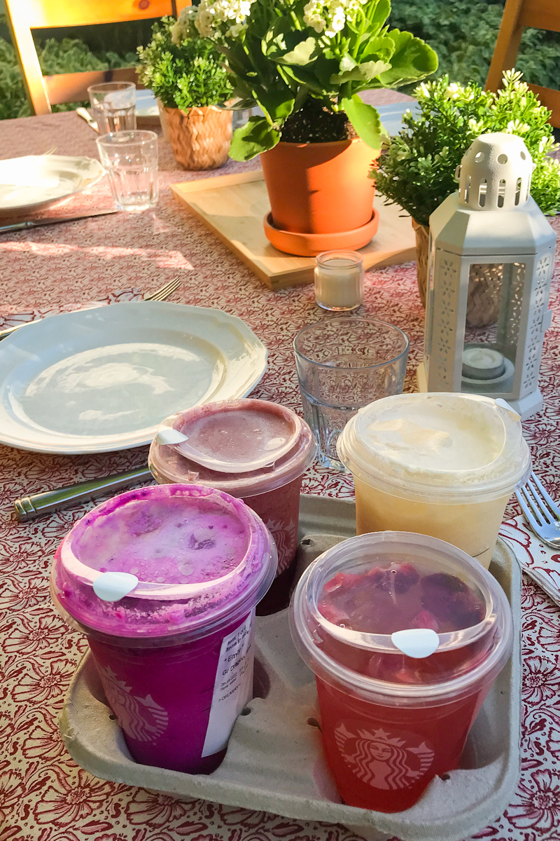 Summer patio table with candles, flowers, and drinks from Starbucks
